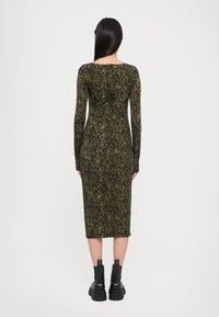 Long-sleeve, fitted dress in green and black leopard print, reaching mid-calf. Worn with black ankle boots featuring thick soles and pull tabs.