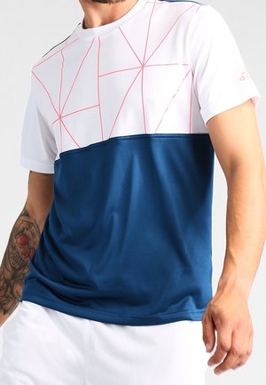Mann trägt ein kurzärmeliges weißes und blaues Sportshirt mit roten geometrischen Linien im oberen Bereich.