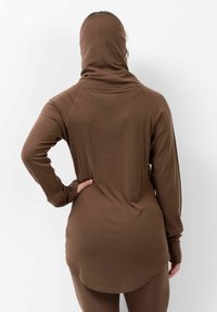 Haut marron à manches longues avec capuche, fabriqué en tissu côtelé. Doté d'un ourlet incurvé et de poignets ajustés, avec une légère texture visible sur le matériau.