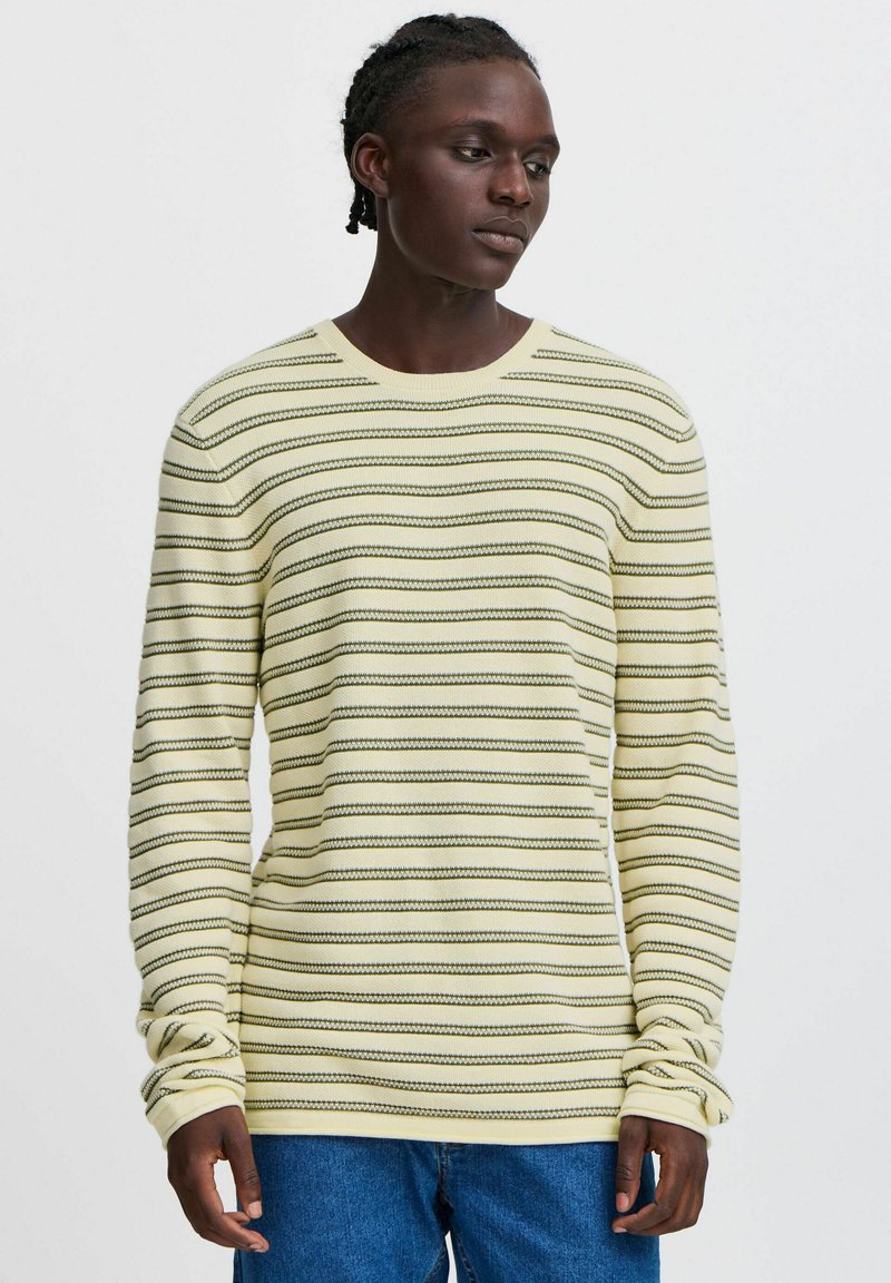 Long-sleeve yellow sweater with horizontal stripes in dark green. Made of knit material. Features a round neckline and ribbed cuffs.