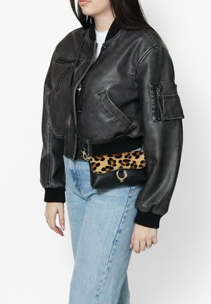 Schwarze Lederbomberjacke mit gerippten Bündchen, kombiniert mit einer kleinen Umhängetasche im Leopardenmuster mit schwarzem Grund und goldenen Beschlägen.