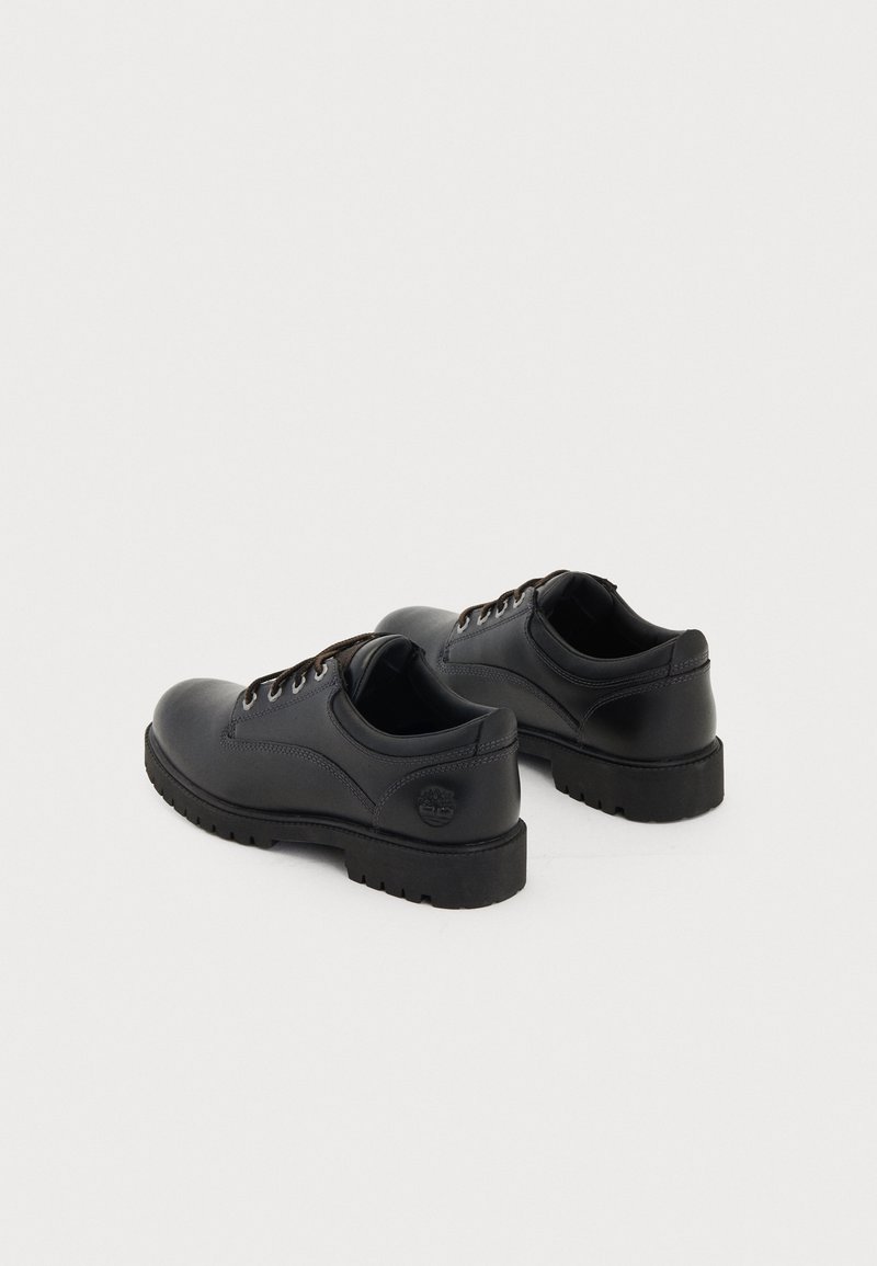 Black leather shoes with a smooth finish, round toe, and lace-up design. Textured rubber sole and logo detail on heel.
