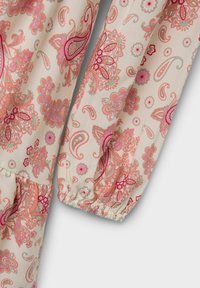 Tissu léger avec un fond crème pastel, présentant un motif paisley coloré dans des teintes de rose et de vert. Poignets de manches élastiques.