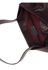 Open dark purple leather handbag with matching strap, burgundy fabric interior, and visible black Tucano brand label.