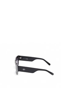 Černé sluneční brýle s geometrickým designem. Mají silné černé rámy, gradientní čočky a kovové akcenty na spáncích.