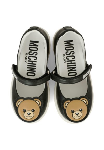 Scarpine per neonati in pelle nera con suola bianca, caratterizzate da un design con faccia d'orso sulla punta e una cinghia attorno alla caviglia. Logo sul fondo.