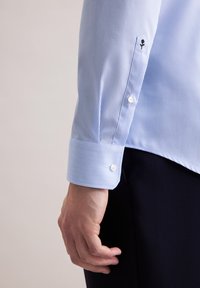 Camicia a righe blu chiaro con colletto a punta e polsini con bottone, dotata di un piccolo logo ricamato. Tessuto di cotone liscio.