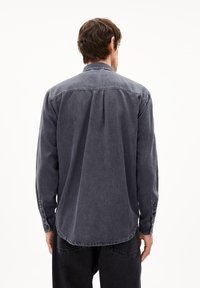 Donkergrijze langarmshirt van denim, met een button-down kraag, een rugplooitje en knoopmanchetten. Zachte textuur met een vervaagd uiterlijk.