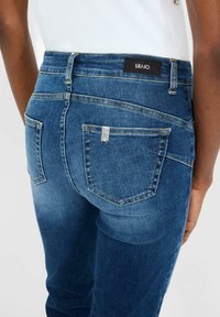 Jeans in denim blu scuro con vestibilità slim, caratterizzati da un'etichetta nera Liu Jo sulla vita e due tasche posteriori con dettagli di cucitura.