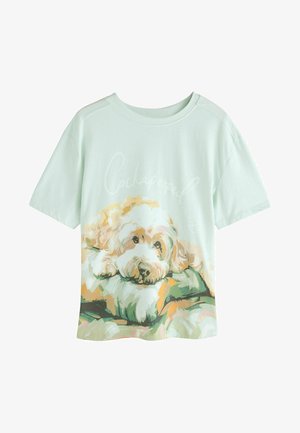 Jasnozielona koszulka z krótkim rękawem z nadrukowanym ilustracją psa odpoczywającego na poduszce, z napisem "Cockapooped."