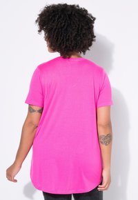 Leuchtend pinkes T-Shirt mit kurzen Ärmeln aus glattem Stoff, mit abgerundetem Saum und lockerem Sitz. Zeigt keine sichtbaren Muster oder Verzierungen.