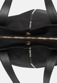 Borsa tote nera con esterno in nylon, zip dorata e manici in pelle. Presenta scomparti con doppia zip e dettagli con il marchio.
