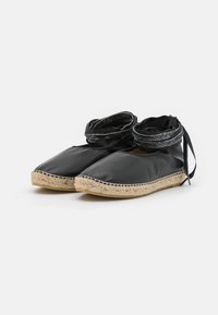 Sapatos de tecido preto com bico redondo, sola de juta trançada e atacadores de fita preta. Textura suave e design simples, adequados para uso casual.