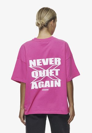 Przesadny różowy t-shirt z białym napisem na plecach "NIGDY WIĘCEJ CICHO", z okrągłym dekoltem i krótkimi rękawami.