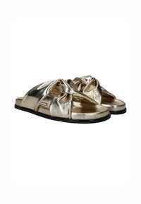 Metalen gouden slide-sandalen met een geknoopt ontwerp aan de bovenkant, voorzien van een platte zwarte zool en een open teenstijl. Zachte en gladde textuur.