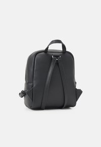 Czarny skórzany plecak o fakturowanej powierzchni, wyposażony w górny uchwyt, regulowane paski oraz zamknięcie na zamek błyskawiczny po jednej stronie.