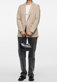 Béžový blazer, bílý top, šedé džíny a černá kabelka s krokodýlím vzorem. Obuv je černá s masivní podrážkou. Jednoduchý, čistý design.