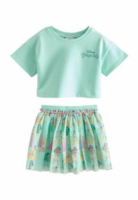 Mündroheline lühikeste varrukatega crop top, millel on kirjas "Disney printsess", kombineeritud kihilise, läbipaistva seelikuga, millel on värvilised printsessi tegelaskujude trükised.
