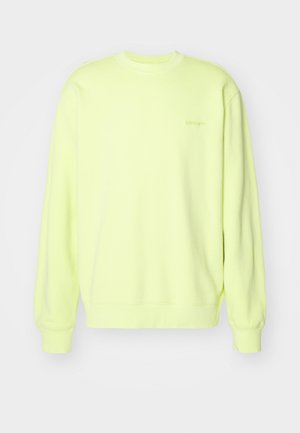 Světlý žlutý svetr vyrobený z měkké látky, s kulatým výstřihem, dlouhými rukávy a žebrovanými manžetami. Na přední straně jemné logo.