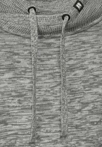 Sudadera de punto gris con un patrón texturizado, que presenta un cuello alto, cordones y una pequeña etiqueta negra cerca del cuello.