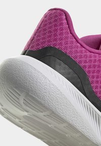 Zapatilla deportiva morada con una parte superior texturizada, banda de acento negra y suela de goma blanca con una superficie de agarre diseñada.