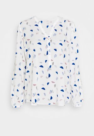 Blouse blanche à manches longues, col en V et patte de boutonnage, présentant un imprimé abstrait dispersé en formes bleues, grises et rouge atténué.