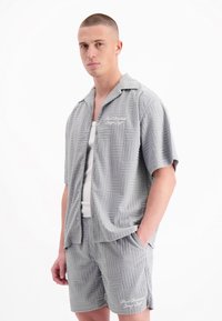 Grijs short-sleeve shirt en korte broeken set gemaakt van textuurstof met een rasterpatroon. Bevat een geborduurd logo in het wit op de shorts.