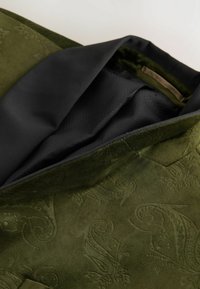 Roheline sametjakk, millel on embossed paisley muster ja must vooder, osaliselt avatud, et näidata tekstuurset kangast seest.