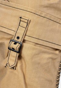 Tissu beige avec un ribbing diagonal, doté d'une boucle noire et de détails de couture. La texture est lisse, avec une finition légèrement brillante.