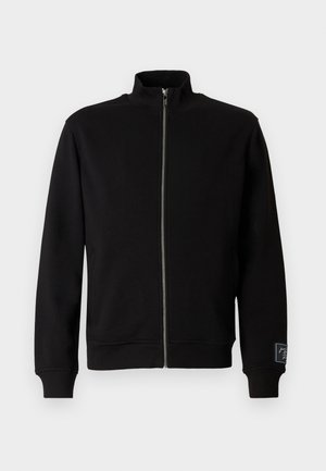 Sudadera negra con cremallera y cuello alto, puños acanalados y una etiqueta lateral. Hecha de un material suave y liso con un diseño de color sólido.