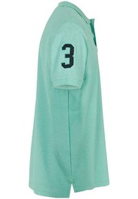 Ljusgrön bomullspolo med korta ärmar, med ett svart nummer "3" på vänster ärm och en treknappsknäppning.