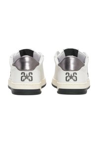Sneakers bianchi con suola in gomma nera, dettagli metallici argentati sul retro e logo impresso. Materiale in pelle liscia con design a bassa altezza.