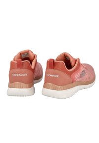 Zapatos Skechers en color durazno con parte superior de malla transpirable y cuello acolchado. Cuenta con una suela de goma y una pestaña en el talón para facilitar el calzado.
