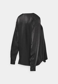 Camisa de seda preta de mangas longas com decote redondo, textura suave e punhos abotoados. A vista traseira destaca um design drapeado.