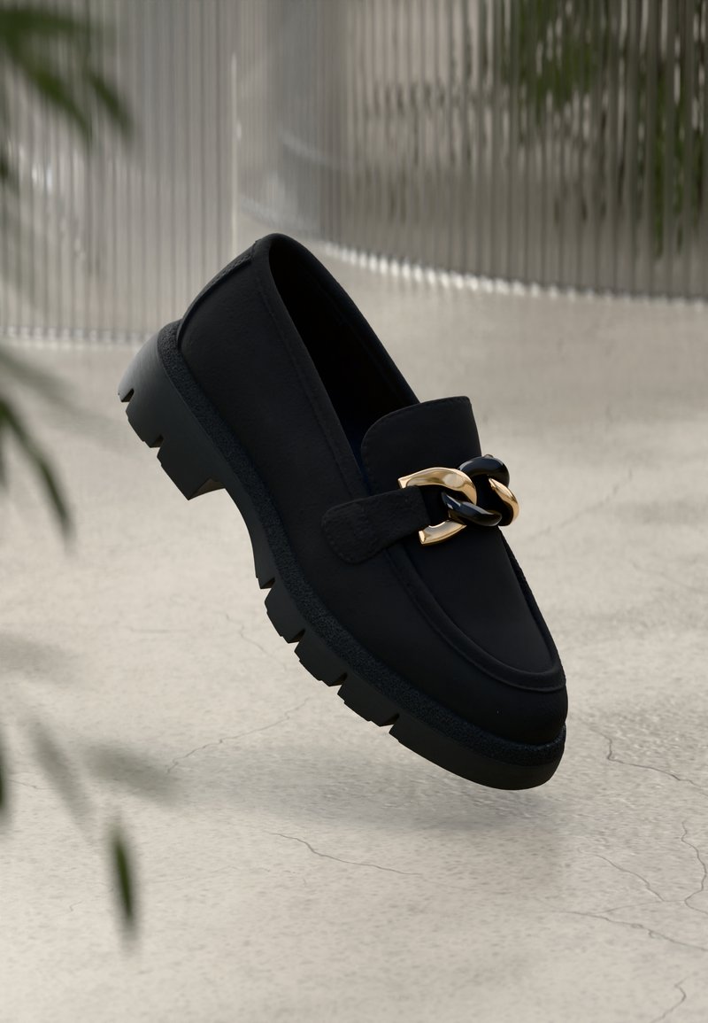 Mustadest nahast moccasinid paksu tallaga, esiküljel kuldse ja musta ketiunistusega. Sile tekstuur ja ümar kuju.