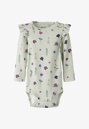 Body bébé à manches longues crème avec imprimé floral violet et bleu, détails à volants sur les épaules, fermetures à pression à l'entrejambe.