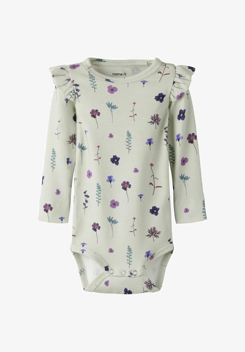 Body bébé à manches longues crème avec imprimé floral violet et bleu, détails à volants sur les épaules, fermetures à pression à l'entrejambe.