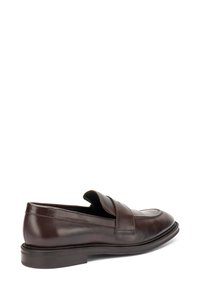 Mocassino in pelle marrone con finitura liscia, punta arrotondata e dettagli a righe sulla parte superiore. Presenta una suola bassa in gomma testurizzata.