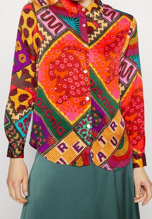 Koszula z długim rękawem na guziki z kolorowymi geometrycznymi i zwierzęcymi nadrukami, w tym czerwonymi lampartami i wzorami patchwork w kolorach pomarańczowym, zielonym, fioletowym i różowym.