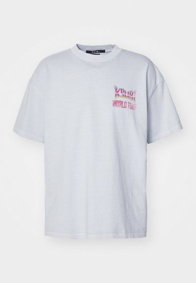 T-shirt de algodão cinza claro com um corte descontraído, apresentando uma gráfica colorida "Ksubi World Tour" no lado esquerdo do peito. Mangas curtas e decote redondo.