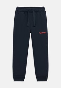 Marineblå sweatpants med elastisk talje og snoretræk. Har "SKATE CREW" broderet i rødt på venstre ben. Blødt, tekstureret stof.