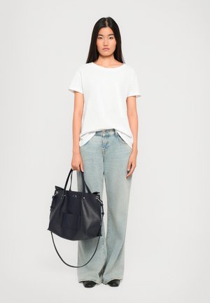 White short-sleeve t-shirt, light blue high-waisted jeans, and a navy leather handbag with silver hardware and a front pocket.