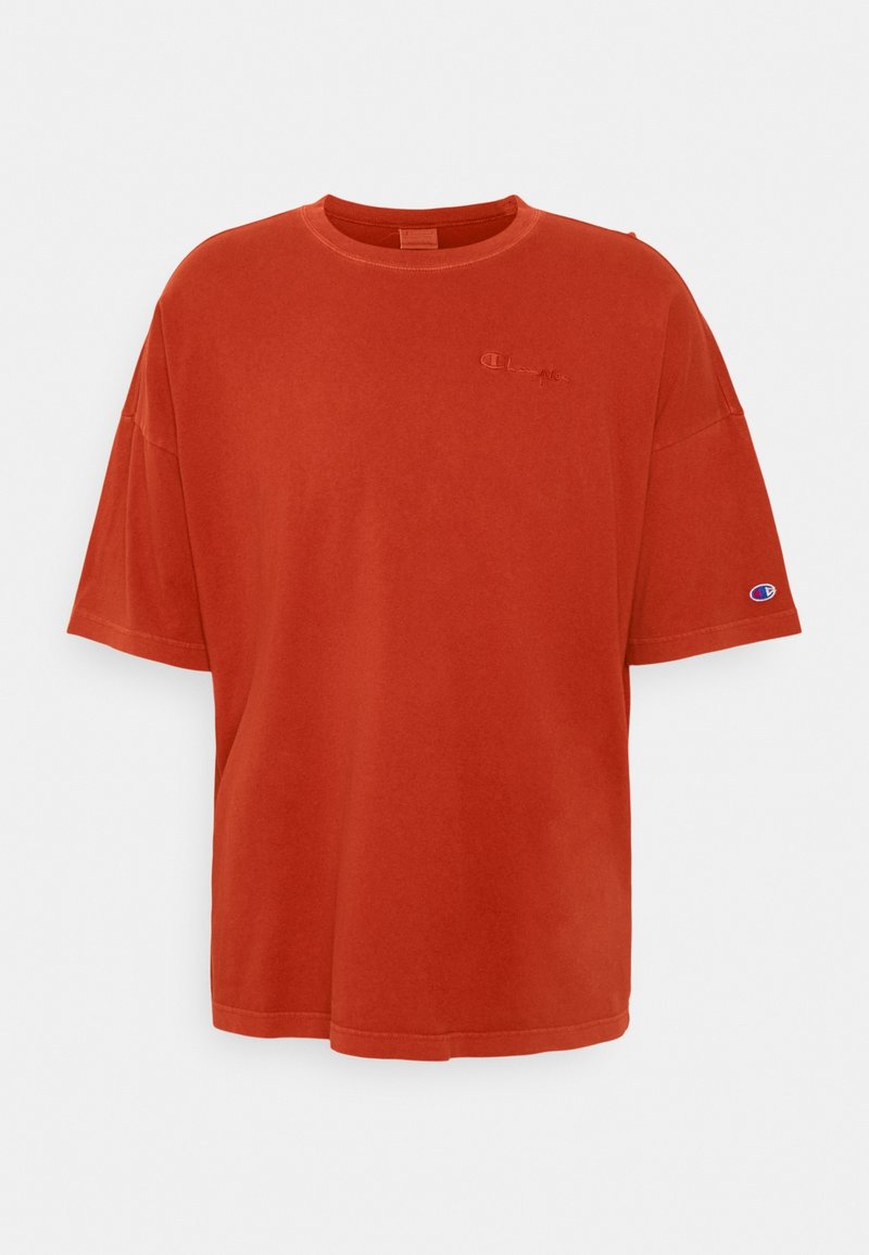 T-shirt en coton orange à coupe ample, manches courtes, col rond, avec un logo brodé sur la poitrine. Conception sans coutures et texture douce.