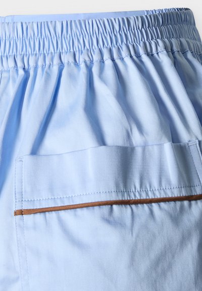 Helehall sinine kangas kummiga vöökohaga ja tagataskuga, millel on pruun äärisdetail, tõenäoliselt osa vabaajajalgpükstest või lühikestest pükstest.