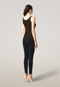 Svart linne kombinerat med marinblå leggings och nude högklackade skor. Linnet har en slät yta och en rundad halsringning.