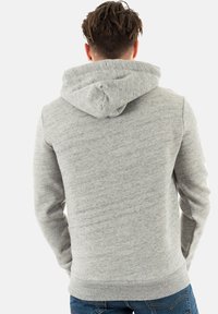 Felpa con cappuccio grigia dal tocco morbido. Presenta una tasca a marsupio e polsini a coste, progettata con una vestibilità comoda.