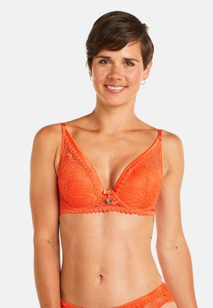 Soutien-gorge en dentelle orange avec une forme triangulaire, des bords festonnés et un fermoir décoratif au centre. Présente des motifs complexes sur toute sa surface.