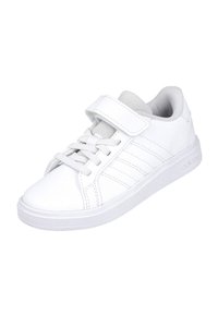 Zapatilla deportiva blanca hecha de cuero suave con suela de goma. Presenta cordones y una tira de velcro. En el lateral tiene tres franjas horizontales.