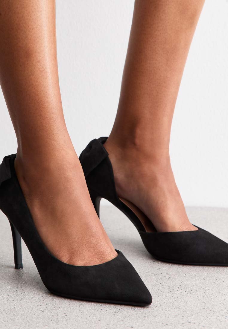 Svarta mocka högklackade skor med spetsad tå och öppen baksida. Har en smal stilettklack och en slät textur. Enkelt design utan utsmyckningar.