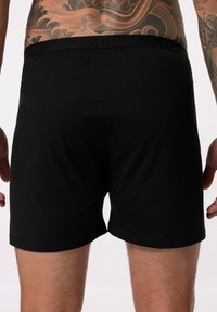 Zwarte katoenen boxershorts met een gladde textuur en een elastische tailleband met merkafdruk, met een eenvoudig en aansluitend ontwerp.